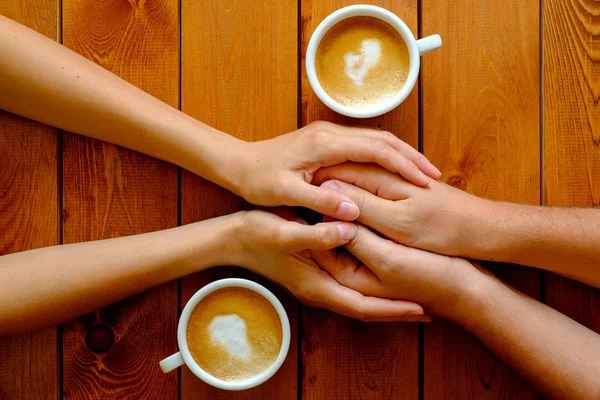 Couple in love holding hands in a cafe, top view