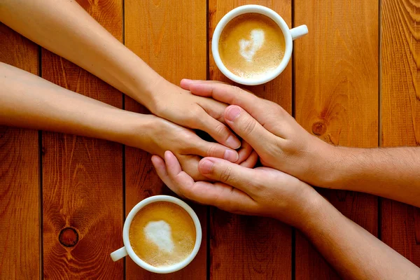 Paar in de liefde hand in hand in een café, bovenaanzicht — Stockfoto