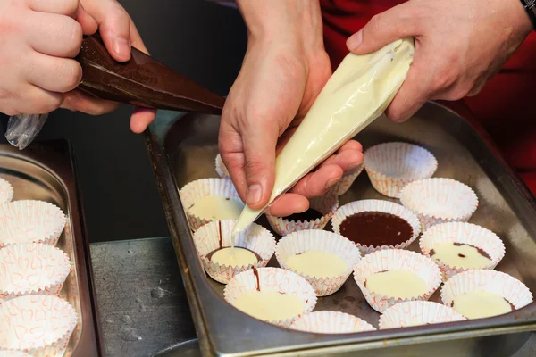 Two chefs fill paper forms Gorgonzola cheese and chocolate and making hot chocolate flan.