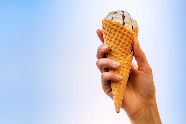 Vanilla ice cream in women's hand on blue background — Stock Photo, Image