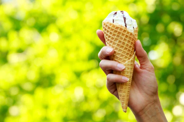 Cone ice cream in women's hand on natural green background — Stock Photo, Image