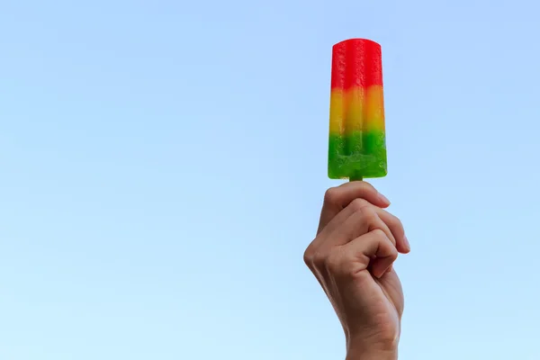 Colorful fruit ice cream in woman hands on blue background — Stock Photo, Image