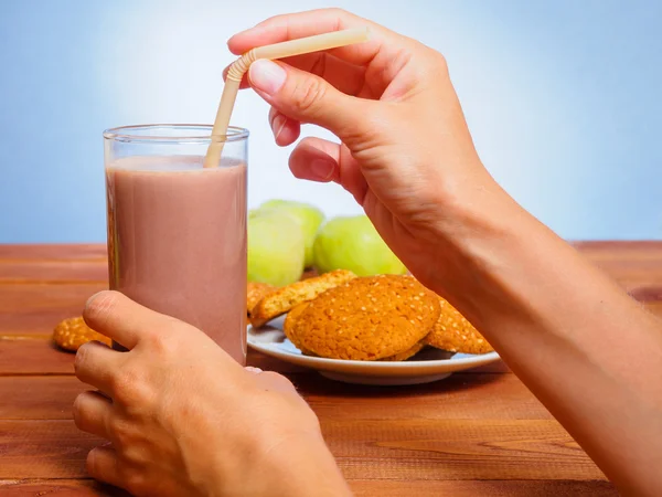 Glass of cocoa with oatmeal cookies. Woman's hand holding a tube. — Stockfoto