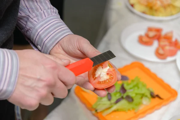 Man in the office cut a tomato with a box cutter — Stock Photo, Image