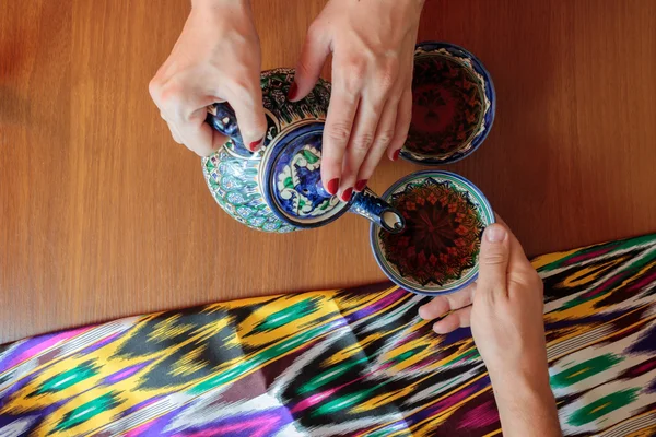 Pouring black tea from teapot in bowl in uzbek restaurant — Stock Photo, Image