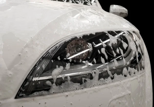 Lavado de autos moderno con jabón. Auto faro cubierto por espuma. — Foto de Stock