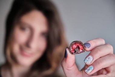 Kadının eli taze kırmızı ve parlak ahududu seçiyor ve alıyor. Ev yapımı siyah beyaz çikolataya batırılmış.