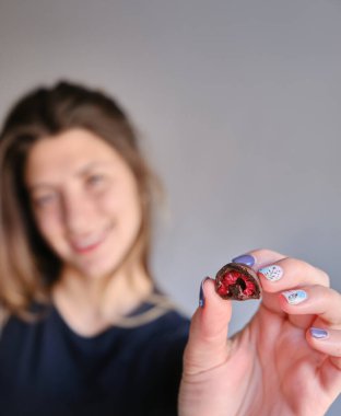 Kadının eli taze kırmızı ve parlak ahududu seçiyor ve alıyor. Ev yapımı siyah beyaz çikolataya batırılmış.