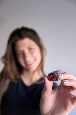 Kadının eli taze kırmızı ve parlak ahududu seçiyor ve alıyor. Ev yapımı siyah beyaz çikolataya batırılmış.