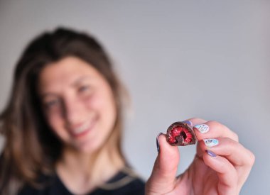 Kadının eli taze kırmızı ve parlak ahududu seçiyor ve alıyor. Ev yapımı siyah beyaz çikolataya batırılmış.