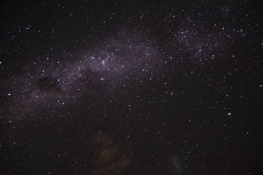 Yıldızlar ve samanyolu ve çevresel bulutsu ile karanlık gökyüzünün uzun bir görüntüsü.