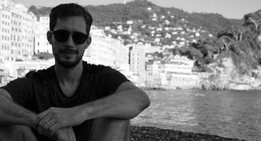 Camogli, Cenova, İtalya sahillerinde renkli evlerin arkasında güneş gözlüğü takan genç bir modelin portresi.