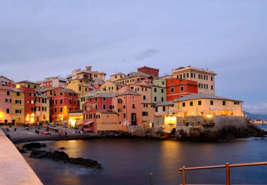 Boccadasse sahilinin renkli evleri ve arkasında yumuşak dalgalar olan uzun pozlu bir fotoğrafı. Cenova, Ligurie, İtalya