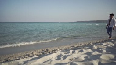 Genç, güzel, melez bir çift gün batımında sahilde yürürken eğleniyor siyah Latin kız arkadaşı kaslı, yakışıklı sakallı adamın omuzlarına atlıyor.