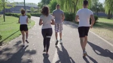 Tanınamaz bir grup melez genç arkadaş sabahın köründe şehir parkında koşuyor - doğada koşan insanların arkasından bakıldığında - sağlıklı bir yaşam için zinde kalmak ve daha iyi yaşamak kavramı