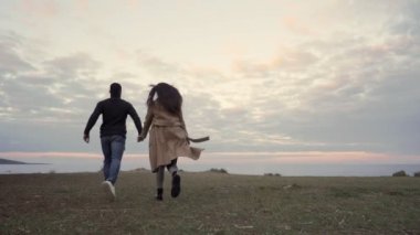 Tanımlanamayan heteroseksüel çiftin el ele tutuşup gün batımında ya da şafakta deniz kıyısına doğru koştuğu romantik yavaş çekim sahnesi.