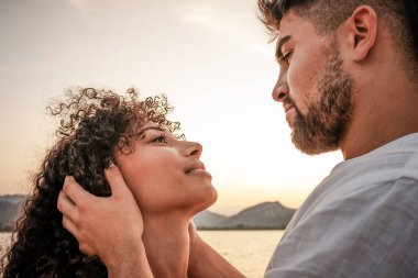 Birbirlerine aşık genç melez bir çiftin gün batımı renklerinde gözlerinin içine bakan portresi. Güçlü bakışları olan itaatkar kadının yüzünü tutan maço, yakışıklı bir adam.