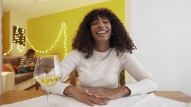 Birlikte yaşayan iki genç kadın internette beyaz şarapla sohbet edip kadeh kaldırıyor. En iyi iki bayan arkadaş kameraya bakıp sohbet ediyor ve gülümsüyor şampanya içiyorlar.