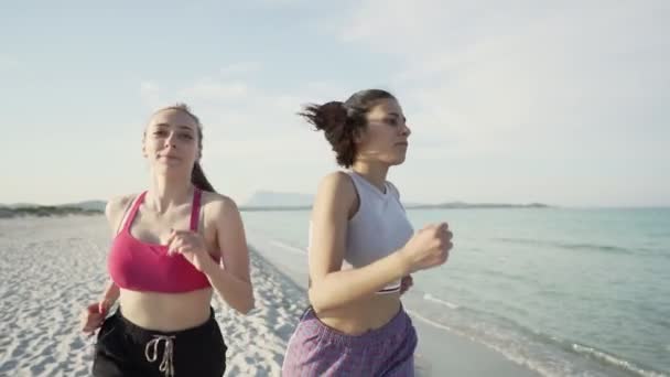两名可爱的女孩在日落时分在海滨的热带海滩上跑着 动作缓慢 以保持健康并保持训练 新的一代处理健康的生活本性 追求更好的生活 — 图库视频影像