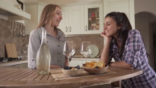 自宅でお祝いする2人の美しい若い女性の友人が注ぐとキッチンでシャンパングラスでクリックしています 女の子は食前酒のために家で一緒にアルコールを飲みながら楽しい時間を過ごして — ストック動画