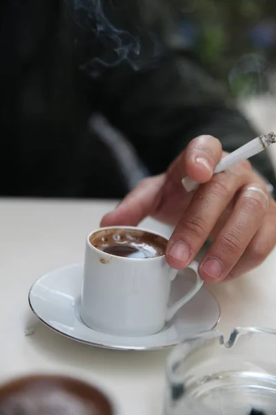 A man with wedding ring drinking coffee with cigarette