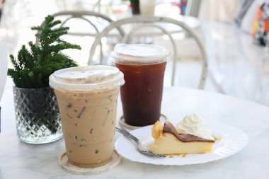 İki buzlu kahve ve arka planda bulanık bir masada bir dilim kek..