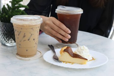İki buzlu kahve ve arka planda bulanık bir masada bir dilim kek..