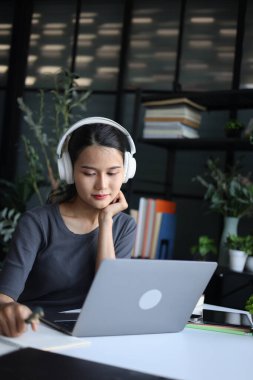 Ofiste çalışan güzel kadınlar, dizüstü bilgisayar kullanıyorlar ve kulaklık takıyorlar..