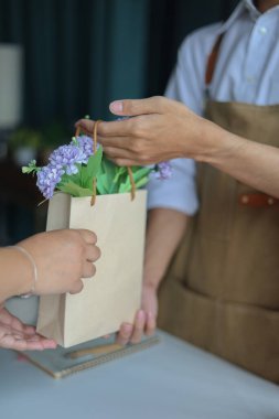 Çiçek dolu bir poşeti müşteriye veren bir çiçekçi. Çiçekçi, küçük işletme, perakende konsepti..