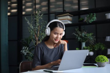 Ofiste çalışan güzel kadınlar, dizüstü bilgisayar kullanıyorlar ve kulaklık takıyorlar..