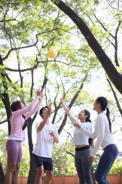 Bir grup arkadaş parkta eğleniyor, zıplıyor, top oynuyor..