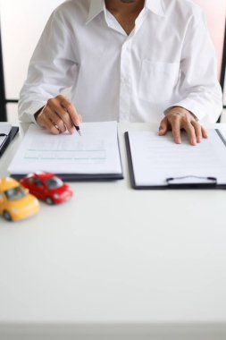 Araba kredisi, kira, araç ruhsatı veya sigorta poliçesi için sözleşme imzalayan bir erkek. Satış Sözleşmesi, Finansman Anlaşması, Sigorta Politikası, Araç Kaydı