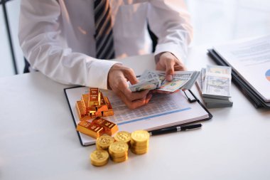 İşadamı altına yatırım yapıyor. İş insanları ve kurumsal yatırımcılara yönelik portföyleri çeşitlendirme stratejisi, enflasyon ve para biriminin değer kaybetmesine karşı koruma ve ekonomik veya jeopolitik belirsizlik süresince güvenli bir sığınak görevi görme stratejisi.