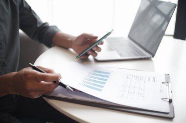 İş yerinde cep telefonu ve dizüstü bilgisayar kullanan işadamının eli.