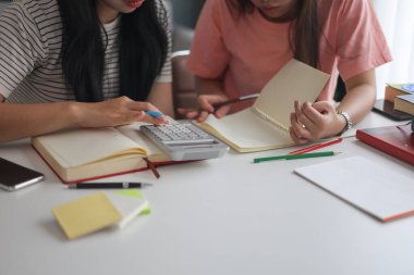 İki kadın öğrenci birlikte ödev yapıyor.