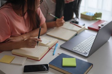 İki kadın öğrenci birlikte ödev yapıyor.