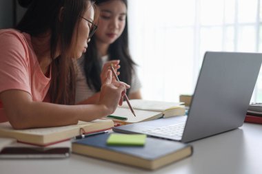 İki kadın öğrenci birlikte ödev yapıyor.