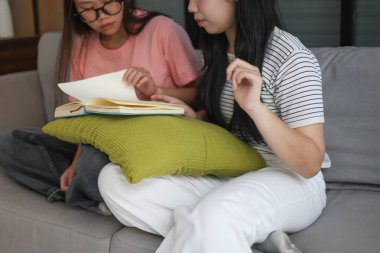 Kanepede kitap okuyan iki kız öğrenci..