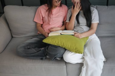 Kanepede kitap okuyan iki kız öğrenci..