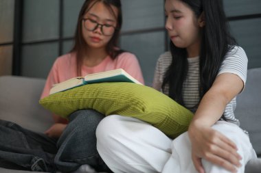 Kanepede kitap okuyan iki kız öğrenci..