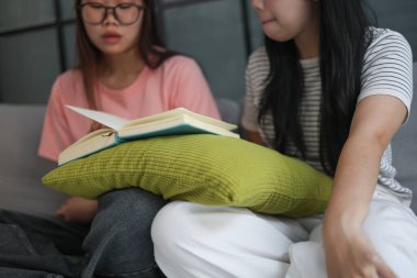 Kanepede kitap okuyan iki kız öğrenci..