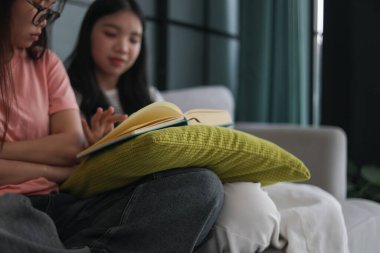 Kanepede kitap okuyan iki kız öğrenci..