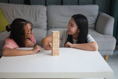 İki genç bayan arkadaş evlerinde tahta kule blokları masa oyunu oynuyorlar..