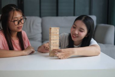 İki genç bayan arkadaş evlerinde tahta kule blokları masa oyunu oynuyorlar..