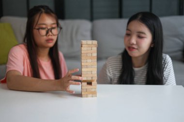 İki genç bayan arkadaş evlerinde tahta kule blokları masa oyunu oynuyorlar..