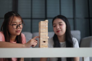 İki genç bayan arkadaş evlerinde tahta kule blokları masa oyunu oynuyorlar..