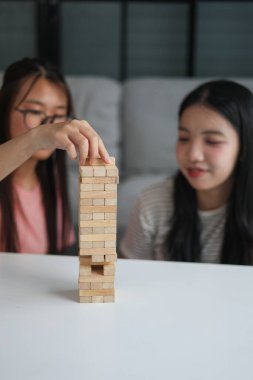 İki genç bayan arkadaş evlerinde tahta kule blokları masa oyunu oynuyorlar..