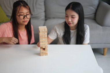 İki genç bayan arkadaş evlerinde tahta kule blokları masa oyunu oynuyorlar..