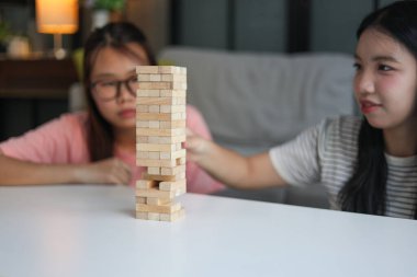 İki genç bayan arkadaş evlerinde tahta kule blokları masa oyunu oynuyorlar..