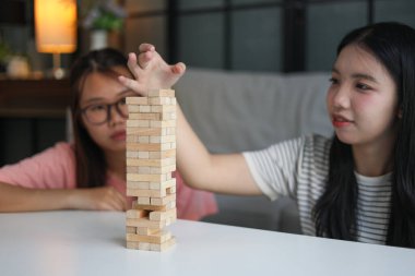 İki genç bayan arkadaş evlerinde tahta kule blokları masa oyunu oynuyorlar..